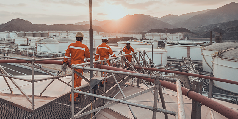 Engineers on terminal roof at refinery at dusk, with mountains in the background