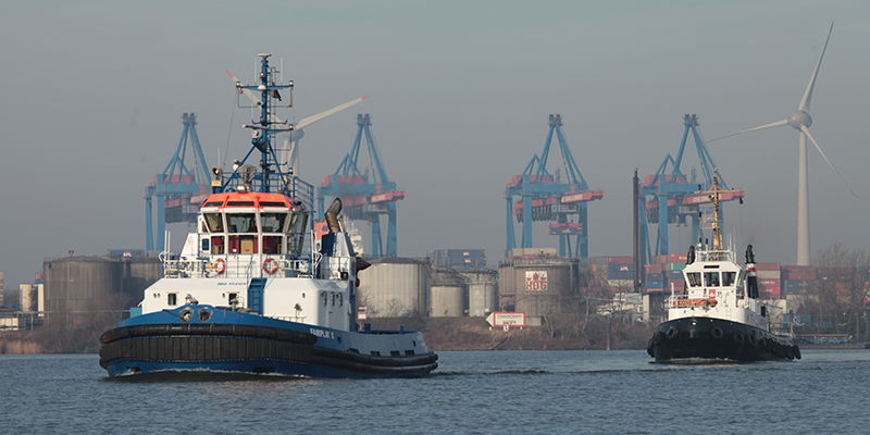 Tugs in the estuary with Rotterdam terminal and wind turbines in background